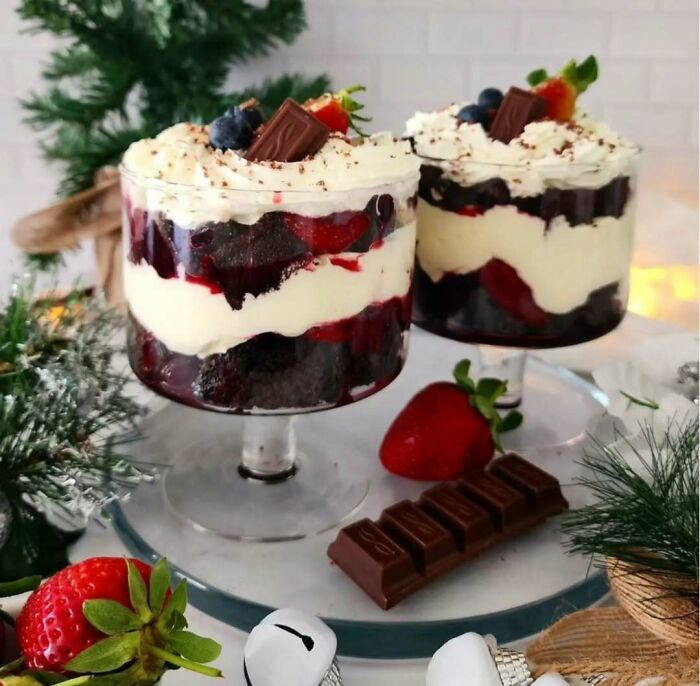 Christmas snack food ideas with layered berry trifle desserts in glass cups, garnished with chocolate and surrounded by festive decor.