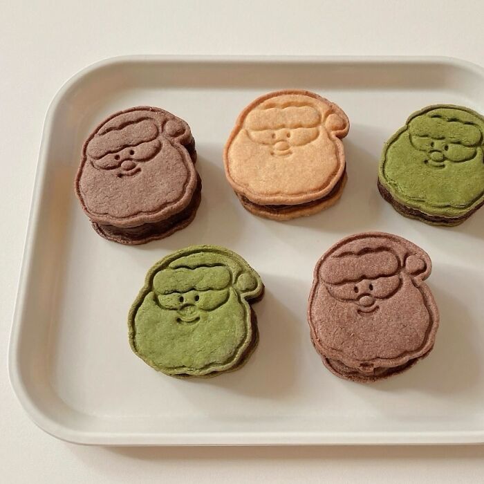 Santa-shaped cookies in various colors displayed on a tray for Christmas snack food ideas.