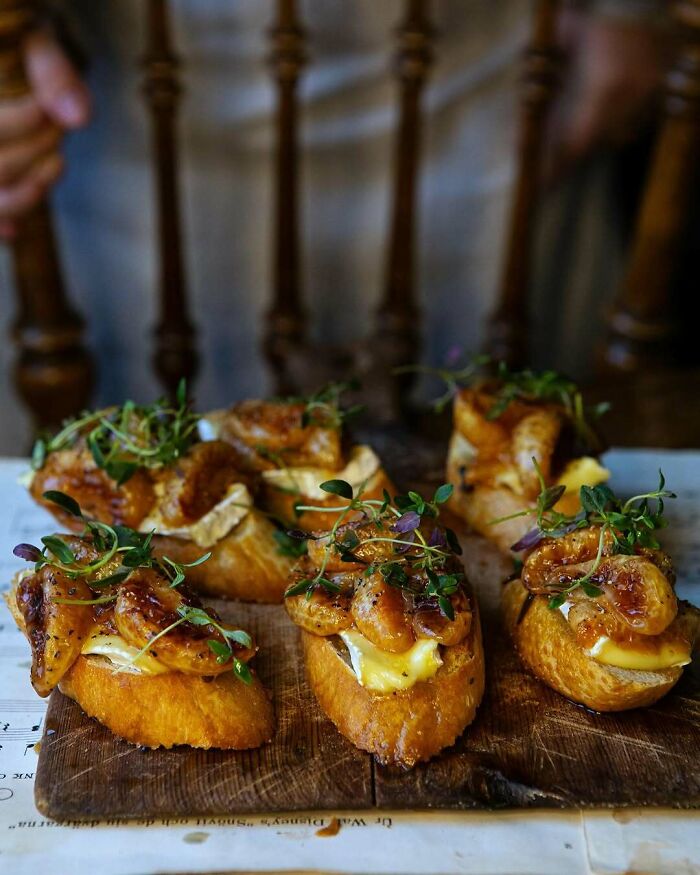 Gourmet crostini with caramelized figs, brie, and microgreens, perfect Christmas snack food ideas on a wooden board.