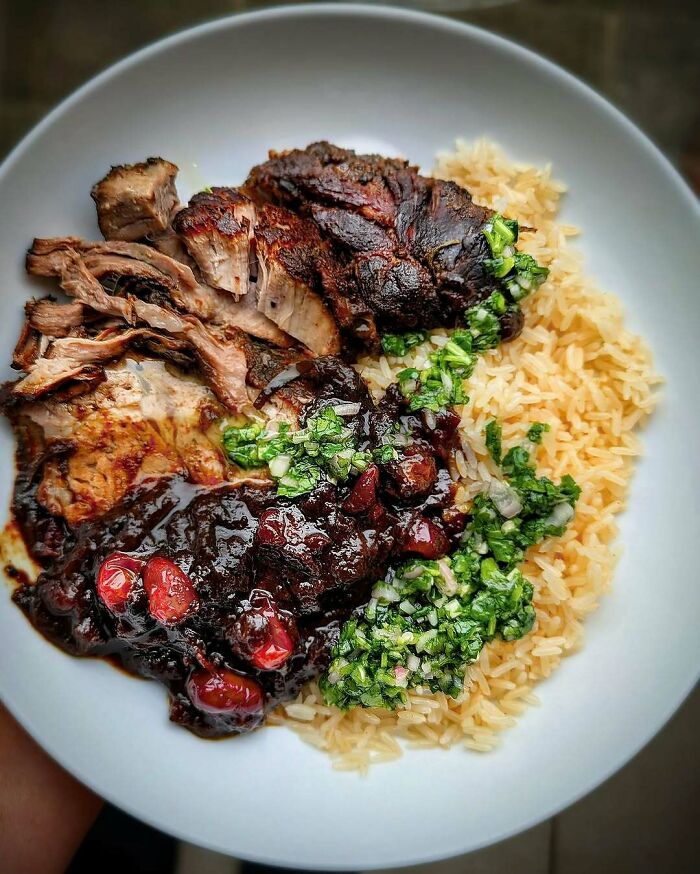 Plate of roasted meat with berry sauce, rice, and herbs, ideal for Christmas snack food ideas.