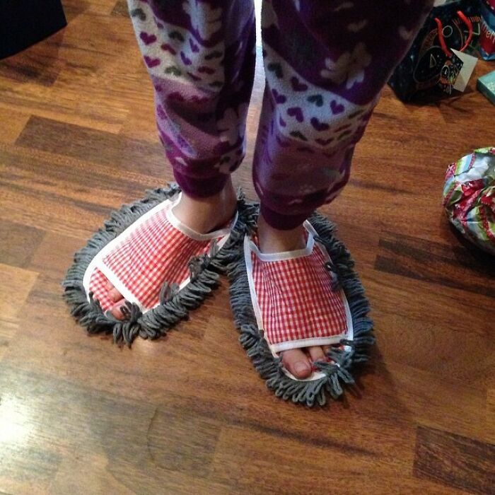 Feet in mop slippers on a wooden floor, a humorous take on Christmas gifts.