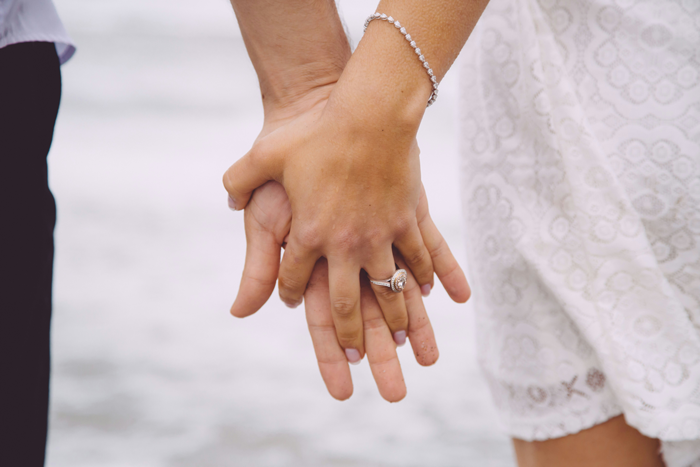 A mom holds her daughter's hand, both wearing rings, symbolizing support and protection.