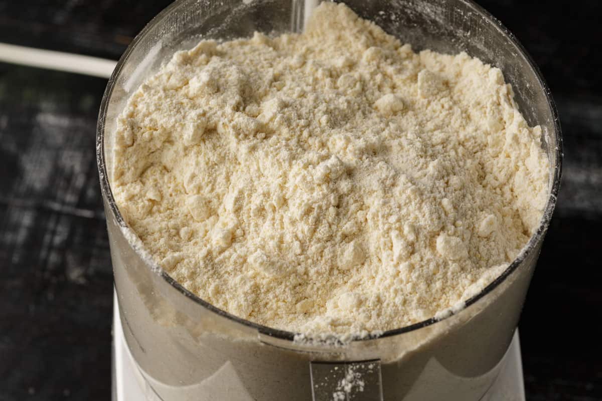 The bowl of a food processor with butter cut into the dry ingredients