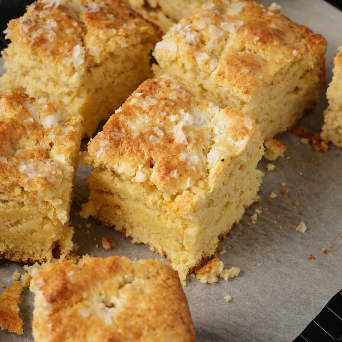 A batch of cornbread biscuits cut on parchment papeer