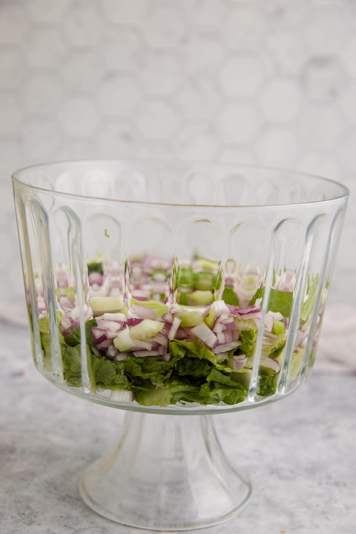 Red onions on top of lettuce in a bowl.