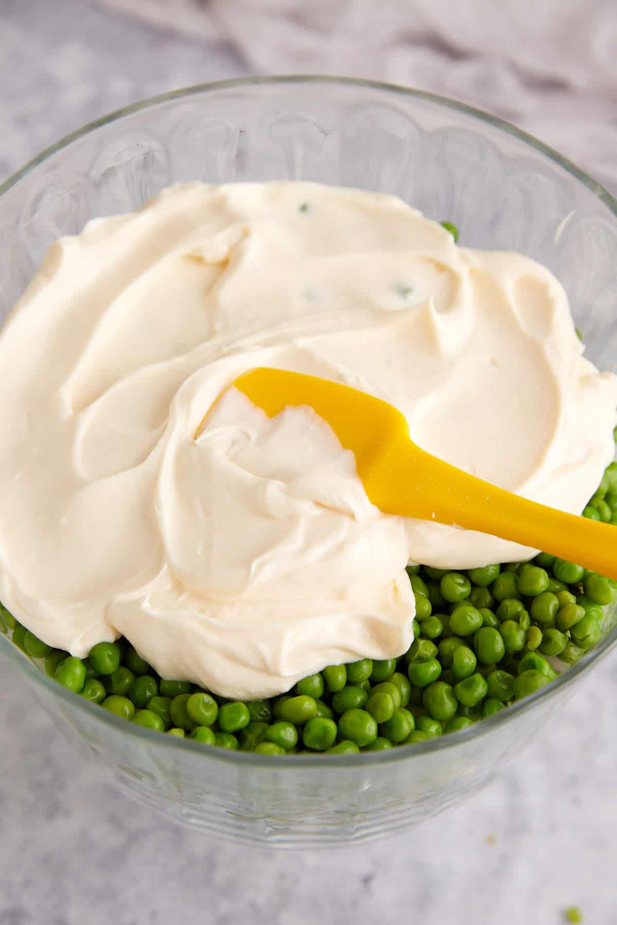 A layer of mayonnaise being spread on top of a 7 layer salad.