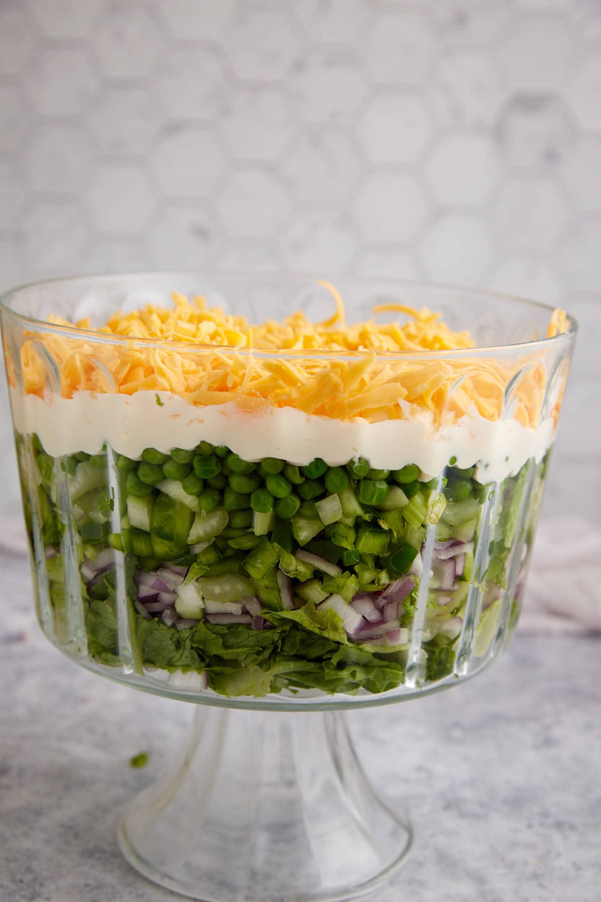 Cheese added to a bowl of seven layer salad