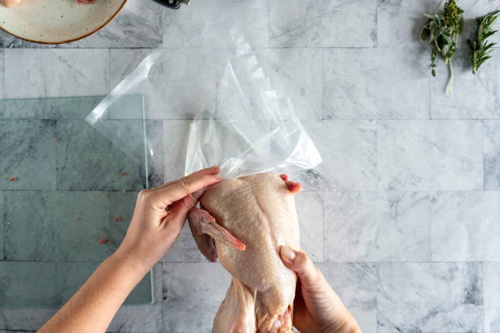 Placing the spatchcocked chicken into vacuum seal bag.