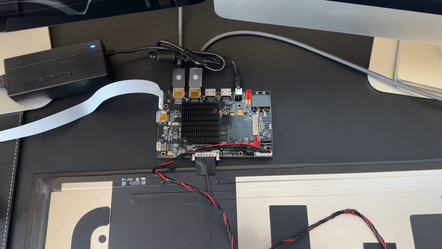 Image showing the replacement display board wired into the iMac display panel, plugged into the power supply and two DisplayPort cables.