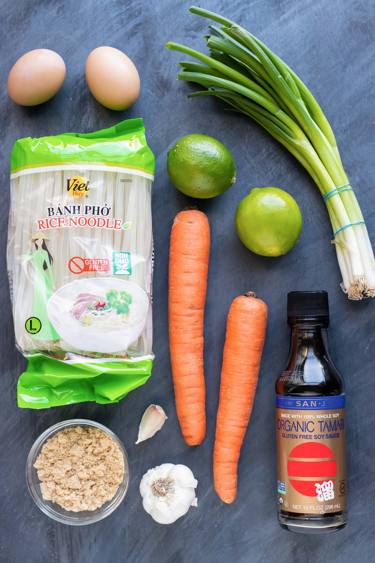 Rice noodles, carrots, lime, green onions, eggs, soy sauce, brown sugar, and garlic as the recipe ingredients.