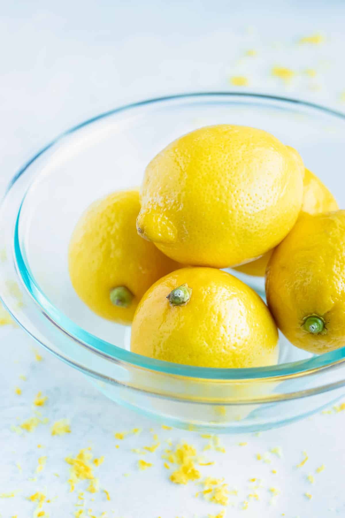 A bowl full of lemons that are waxed and unwaxed.