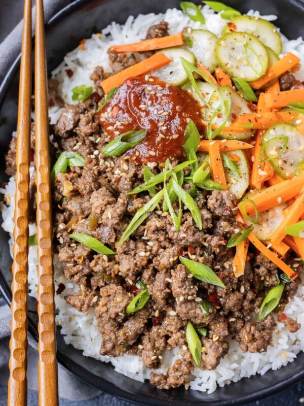 An easy homemade korean beef recipe is served with gochujang and pickled veggies with chopsticks.