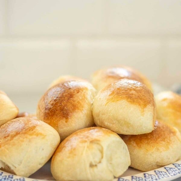 Sourdough brioche rolls stacked on a blue and white plate.