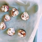 Close up of figs with goat cheese, honey and black pepper on parchment.