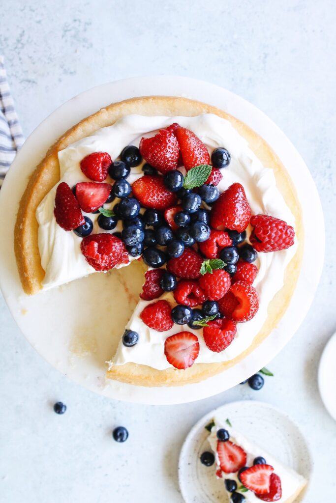 berries and cream cake on a white cake plate