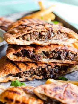 Pita stuffed with ground beef and grilled, stacked in a pile of three