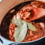 Sauteed onions with spices, broth and bay leaves in a large light mint pot on a marble background