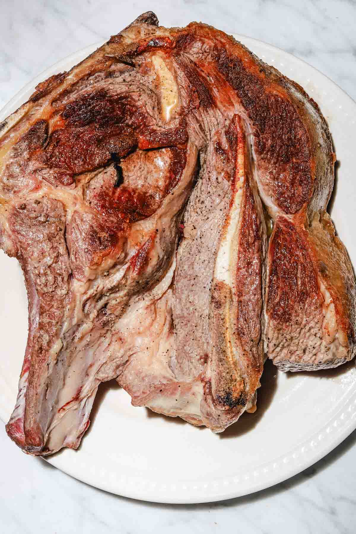 seared bone in chuck on an oval platter on a light marble background