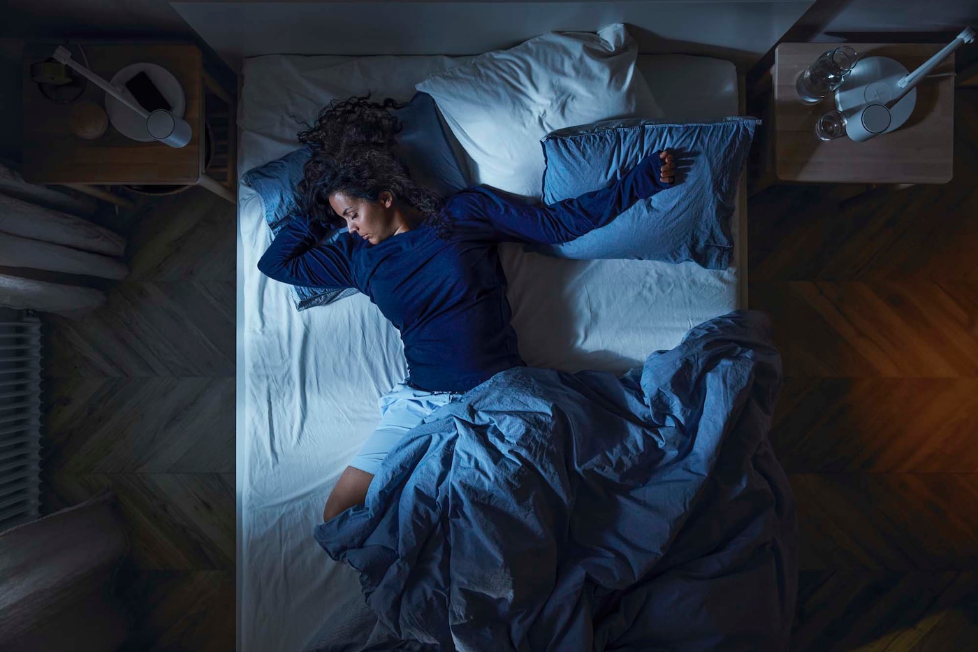 Overhead view of a person sleeping on a bed in a dark room.