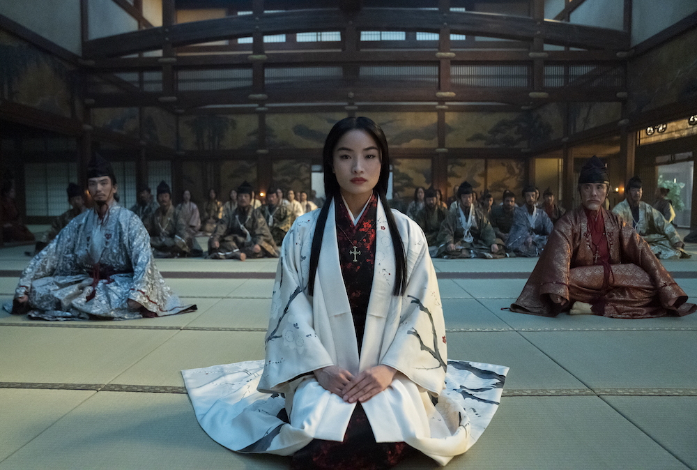 Eita Okuno as Saeki Nobutatsu, Anna Sawai as Toda Mariko, Hiromoto Ida as Kiyama Ukon Sadanaga sit on the floor of a large room, legs folded, robes worn, in 'Shogun'