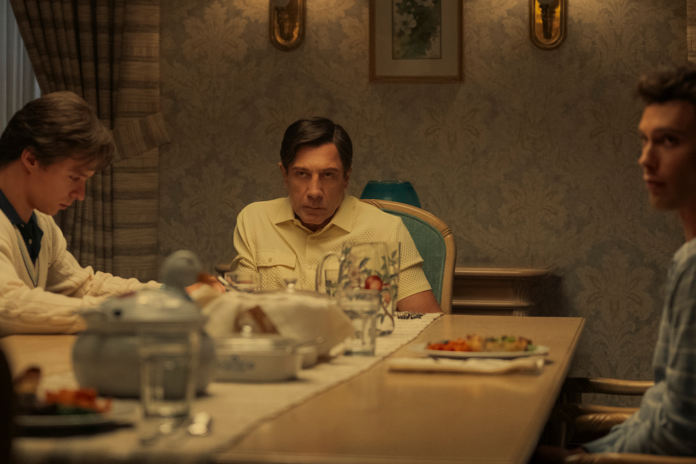 Monsters: The Lyle And Erik Menendez Story stars Nicholas Chavez as Lyle Menendez, Javier Bardem as Jose Menendez, Cooper Koch as Erik Menendez, shown here sitting ominously around the dinner table