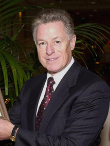 Smiling, middle-aged man with graying hair, wearing a suit and tie.