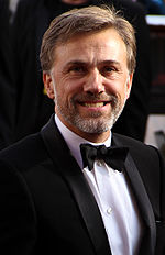 A middle aged man wearing a tuxedo faces forward while smiling.