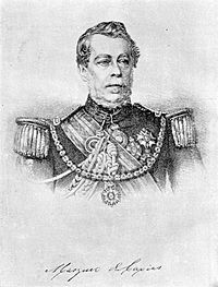 Lithograph depicting head and shoulders of a man with gray moustache wearing a military tunic with epaulettes and elaborate lanyards, several medals at his neck and breast, sash of office, and a prominent star on a heavy gold chain suspended from his shoulders