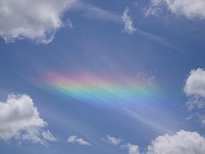 A circumhorizontal arc projected onto a sheet of striated cirrus clouds seen through a hole in lower-level cumulus clouds.