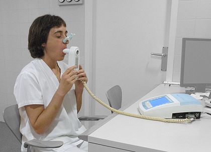 A person sitting and blowing into a device attached to a computer