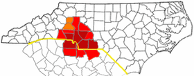 Counties most commonly associated with Metrolina are in dark red, counties often included are light red, and counties sometimes included are in orange. The NC/SC state line is shown in yellow.