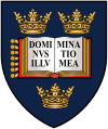 A shield displaying a coat of arms; on a dark blue background, an open book displays the words "Dominus Illuminatio Mea"; two gold crowns above, one below