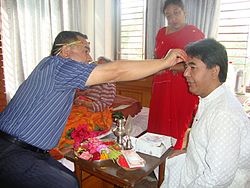 Family member marking the forehead of another member, with other family members watching