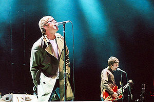 Oasis performing onstage, singing into microphones