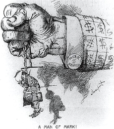 A political cartoon. A closed fist protrudes from a jacket-sleeve covered in dollar signs; a cuff-link is marked "MARK $ HANNA". The hand tightly grasps a chain from which hangs a tiny, sorry-looking figure marked "McKinley". "A Man of Mark!" concludes the cartoon's caption.