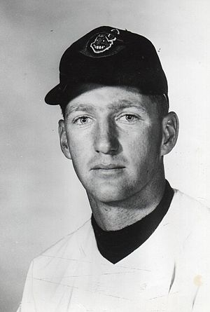 A man in a light baseball jersey and dark cap