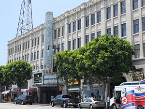 A street view of a wide, white building. In the center is a large vertical sign that says "Pacific".