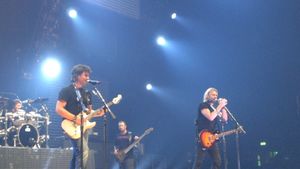 A color photo of four band members on stage, in the foreground the audience can be seen.