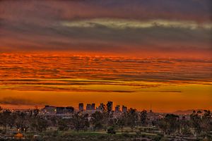 a photo of the reds and oranges of a sunset over the skyline of Phoenix, as seen from Papago park.