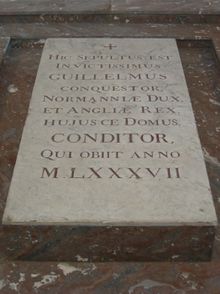 A stone slab on the ground with carved lettering on it