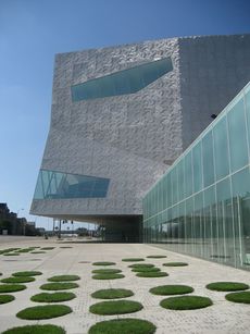 Modern building in bright sunlight with circles of grass in foreground