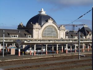 Train station with large, domed building and a high-speed train at the platform