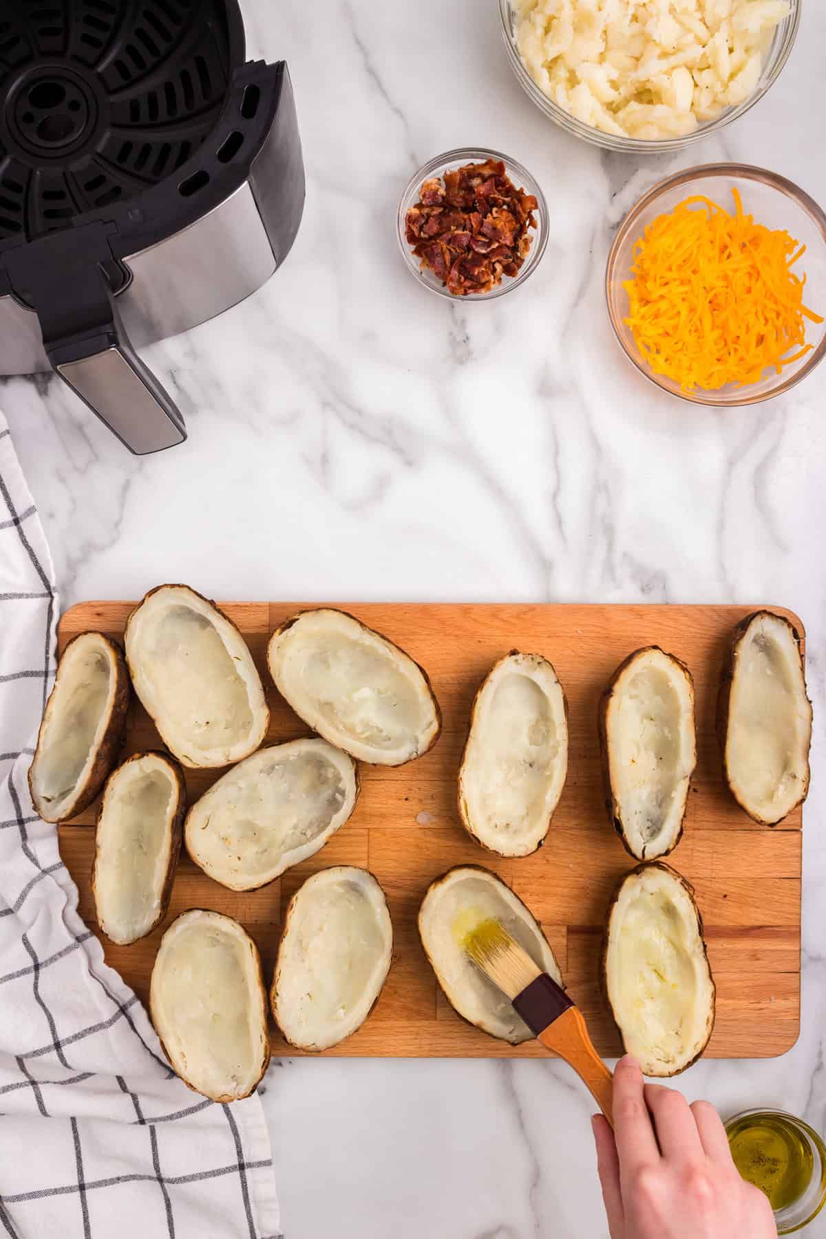 Hallowing out cooked potatoes and brushing with olive oil  for Air Fryer Potato Skins recipe