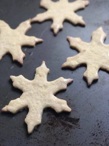 Snowflake Cookies on a dark gray sheet pan