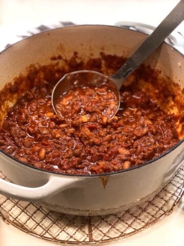 Dutch oven chili in Dutch oven with a ladle.