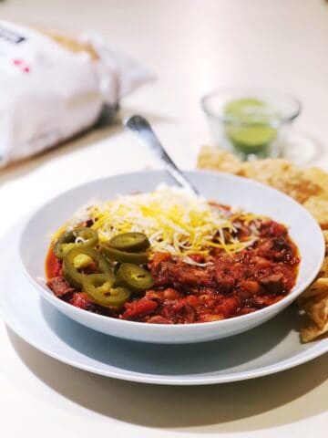 smoked brisket chili with toppings in a bowl on the counter.