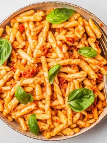 Casarecce pasta in a bowl with fresh basil on top.