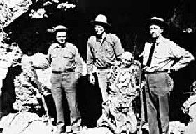 Posse, who recovered Queho's remains, stands at the mouth of his cave hideout. From left, Clarke Kenyon, Frank Wait, and Art Schroeder.