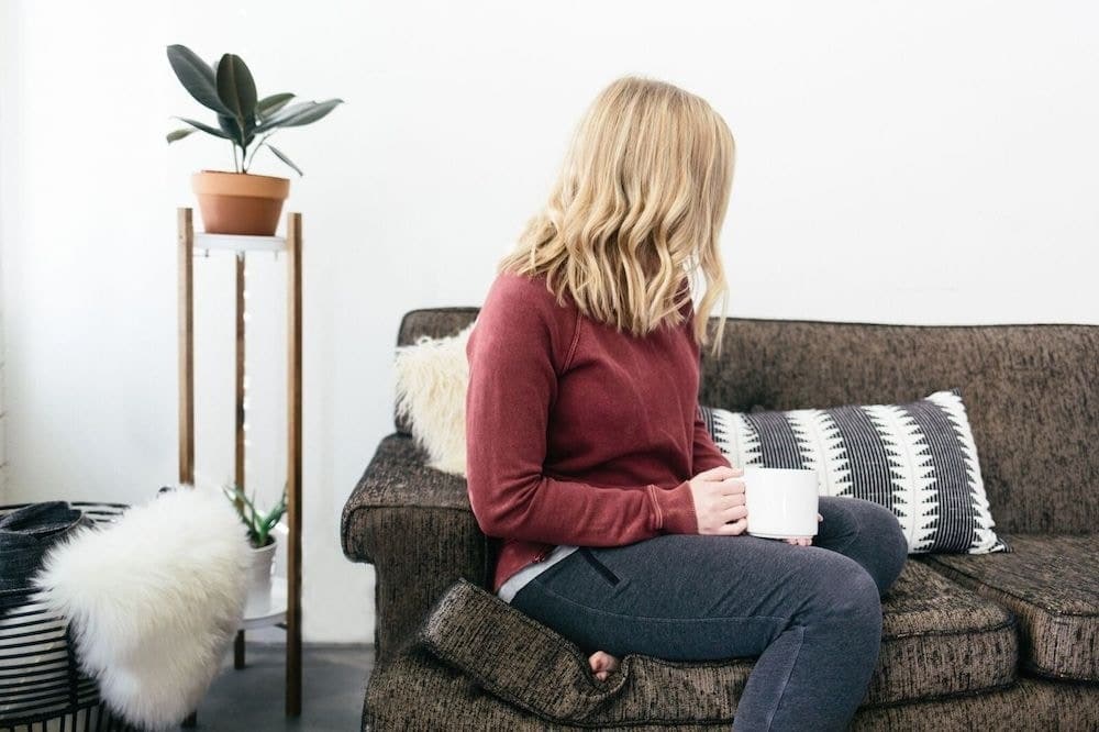 woman sitting with a cup of coffee on a couch