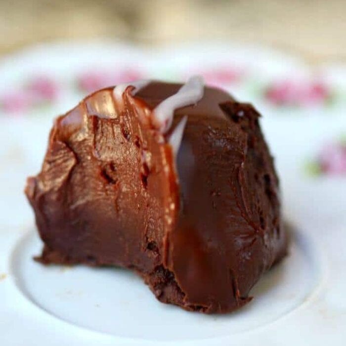 Closeup of a chocolate truffle with a bite taken out of it.